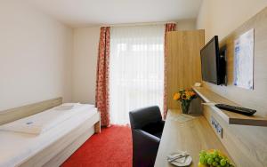 a room with a bed and a desk with a television at Lindenhof in Osterspai