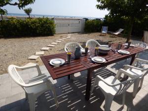 une table en bois entourée de chaises blanches dans l'établissement Villa T5 climatisée - Front de Mer - Narbonne Plage, à Narbonne-Plage