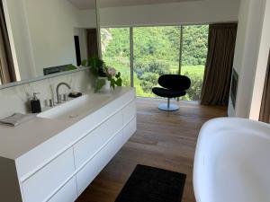 uma casa de banho com um lavatório e uma cadeira preta em La Forestale Luxury Ecolodge - La Suite Royale em Acqualagna