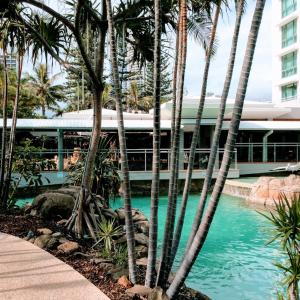a pool with palm trees in front of a building at Crown Towers Resort Private Apartments in Gold Coast