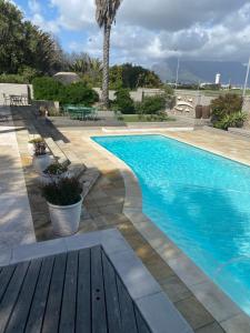 una grande piscina con terrazza in legno accanto ad essa di Cotswold House Residence a Città del Capo