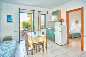 eine Küche und ein Wohnzimmer mit einem Tisch und einem Kühlschrank in der Unterkunft Dionysos Apartments & Studios in Stalida