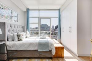 Un dormitorio con una cama grande y una ventana grande. en Backup-Power Eclectic Blue City View Apartment, en Ciudad del Cabo