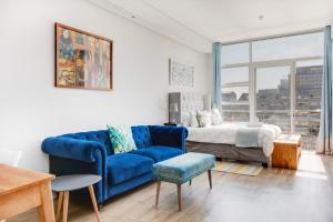 sala de estar con sofá azul y cama en Backup-Power Eclectic Blue City View Apartment en Ciudad del Cabo