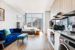 Una sala de estar con un sofá azul y una cama. en Backup-Power Eclectic Blue City View Apartment, en Ciudad del Cabo