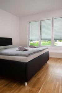 Cama en habitación blanca con ventanas en Villa de Roya, en Rogaška Slatina