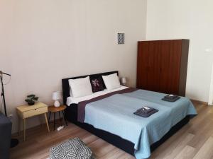 1 dormitorio con 1 cama grande con manta azul en Palace - Belvárosi Apartman Eger en Eger