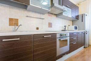 a kitchen with wooden cabinets and a stove top oven at Apartments on Darnitsa in Kyiv
