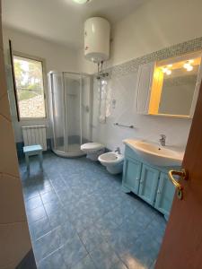 een badkamer met 2 wastafels, een douche en een toilet bij Casa Serena in Capoliveri