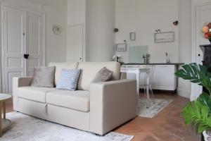 a white couch in a living room with a kitchen at CHIC ANDREOSSY-COSY-AUTHENTIQUE-WI-Fi-Vélo in Castelnaudary