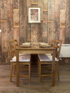 a wooden table with chairs and a wooden wall at Appartement FrontierHome à deux pas de Disneyland in Bailly-Romainvilliers