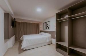 a bedroom with a bed and some shelves at Manaíra Apart Hotel in João Pessoa