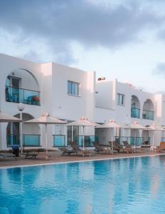 a hotel with a swimming pool with chairs and umbrellas at Kaos Hotel Apartments in Ayia Napa