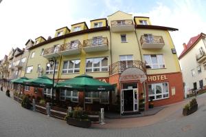 a large building with green umbrellas in front of it at Secession Hotel in Łęczna