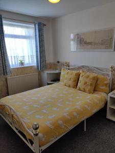 a bedroom with a bed with yellow sheets and a window at Cameron court B&B in Flamborough