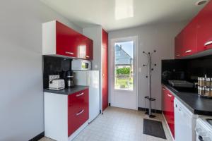 eine Küche mit roten Schränken und einem weißen Kühlschrank in der Unterkunft La Petite Isle - Maison et jardin - plage à 200 m in Barneville-Carteret + 9 Fotos