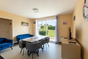 ein Wohnzimmer mit Tisch und Stühlen und einem Fernseher in der Unterkunft La Petite Isle - Maison et jardin - plage à 200 m in Barneville-Carteret