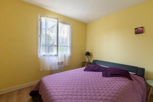 ein Schlafzimmer mit einem lila Bett und einem Fenster in der Unterkunft La Petite Isle - Maison et jardin - plage à 200 m in Barneville-Carteret