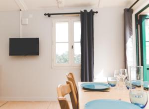 een eetkamer met een tafel met stoelen en een televisie bij Terres de France - Domaine de Kerioche in Rochefort-en-Terre