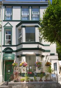 Un bâtiment blanc avec des fleurs devant lui dans l'établissement The Firs Bed and Breakfast, à Plymouth