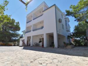 a large white building with a stone driveway at Apartments M in Pirovac