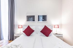 una camera da letto con un letto bianco con cuscini rossi di The Levante Rathaus Apartments a Vienna Altre 37 foto