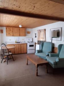 a living room with two chairs and a table and a kitchen at Algonquin Lakeside Inn in Dwight