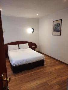 Cette chambre comprend un lit avec des draps blancs et du parquet. dans l'établissement Le Clémenceau Hôtel et Appart'hôtel & Restaurant "Gare Sncf" centre ville, à Valenciennes