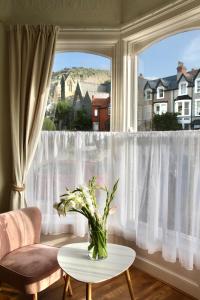 a vase of flowers on a table in front of a window at Mostyn Villa in Llandudno