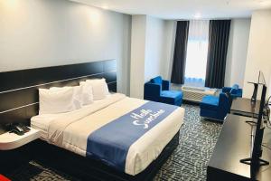 a hotel room with a large bed and blue chairs at Days Inn & Suites by Wyndham Horn Lake - Memphis Graceland in Horn Lake