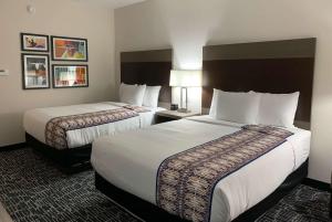 a hotel room with two beds with white sheets at La Quinta Inn & Suites by Wyndham - Red Oak TX IH-35E in Red Oak