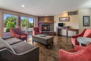 a living room with a fireplace and red chairs at Quality Inn & Suites Downtown Walla Walla in Walla Walla