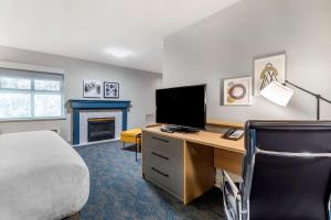 um quarto com uma cama e uma secretária com uma televisão em Clarion Hotel & Conference Centre em Abbotsford