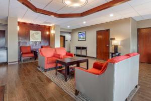 a waiting room with red chairs and a table at Comfort Suites in Escanaba
