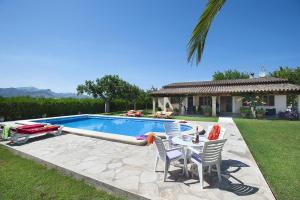 a pool with chairs and a table and a house at Villa BURGUES in Alcudia