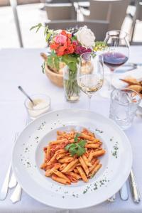 une assiette blanche de pâtes sur une table avec des fleurs dans l'établissement Hotel Bemelmans-Post, à Collalbo