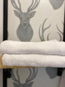 a stack of towels on a rack with a deer on the wall at Pokoje w Starej Karczmie in Liszki