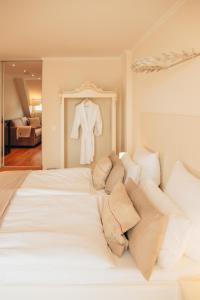 a white bed with a robe hanging on a wall at Boutique Hotel Classico Bremen in Bremen