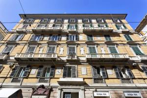 wysoki żółty budynek z oknami i balkonami w obiekcie Boutique Apartment in Via Roma by Wonderful Italy w Genui