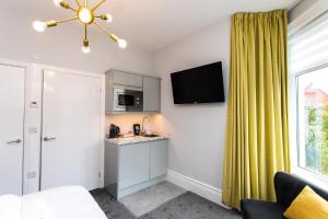 a living room with a kitchen and a yellow curtain at Stay Coastal in Whitley Bay