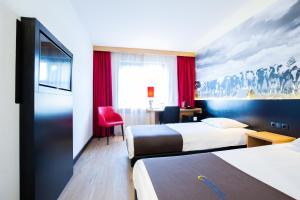 a hotel room with two beds and a red chair at Bastion Hotel Roosendaal in Roosendaal