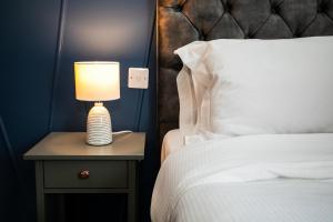 a lamp on a night stand next to a bed at Stay Coastal in Whitley Bay