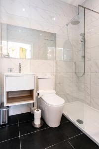 a white bathroom with a toilet and a shower at Stay Coastal in Whitley Bay
