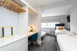a bedroom with two beds and a desk in a room at Stay Coastal in Whitley Bay