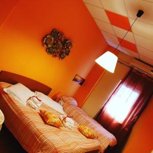 2 Betten in einem Zimmer mit orangefarbenen Wänden in der Unterkunft Oasi B&B in Benevento