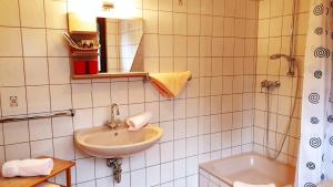 a white tiled bathroom with a sink and a tub at Haus Scheuten Hotel in Duisburg