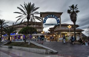 a shopping center with palm trees in front of it at Casa Capitan con vista mar in Arona +10 photos