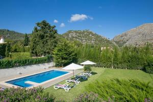 a garden with a swimming pool and chairs and umbrellas at Villa LLOBINER in Pollença