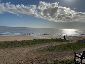 a bench on a beach with people in the water at Stay Coastal in Whitley Bay