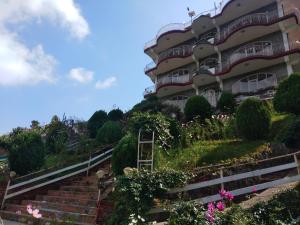 a building with stairs and flowers in front of it at Hotel Victoriya palace in McLeod Ganj